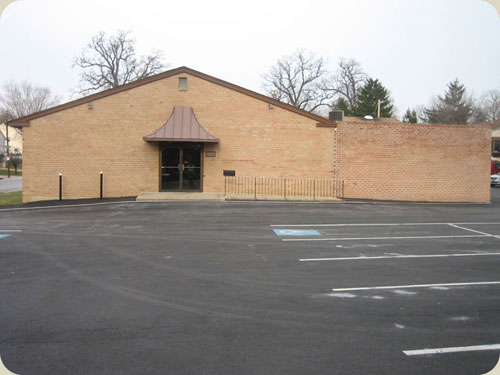 Photo taken outside showing parking lot, enterence, and handicap access